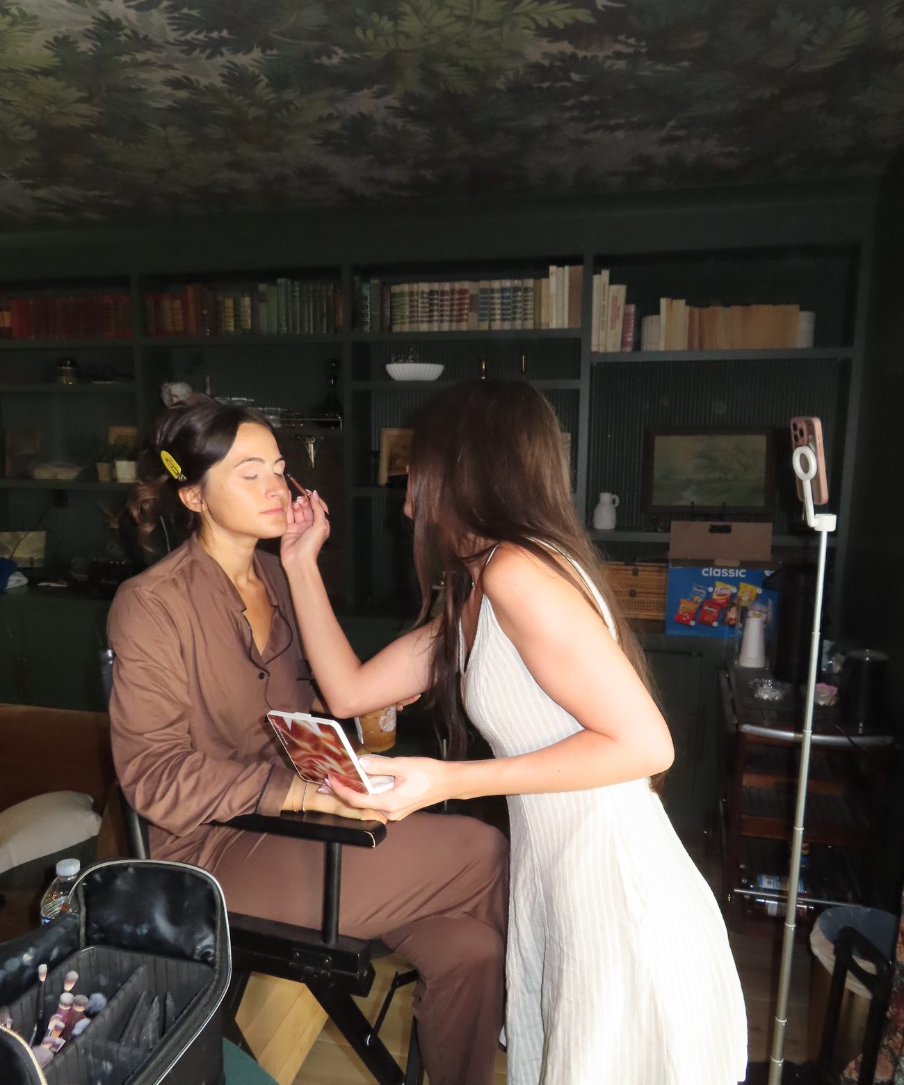 Samantha at work on-location — applying eye makeup to a client in a cozy, warmly-lit room