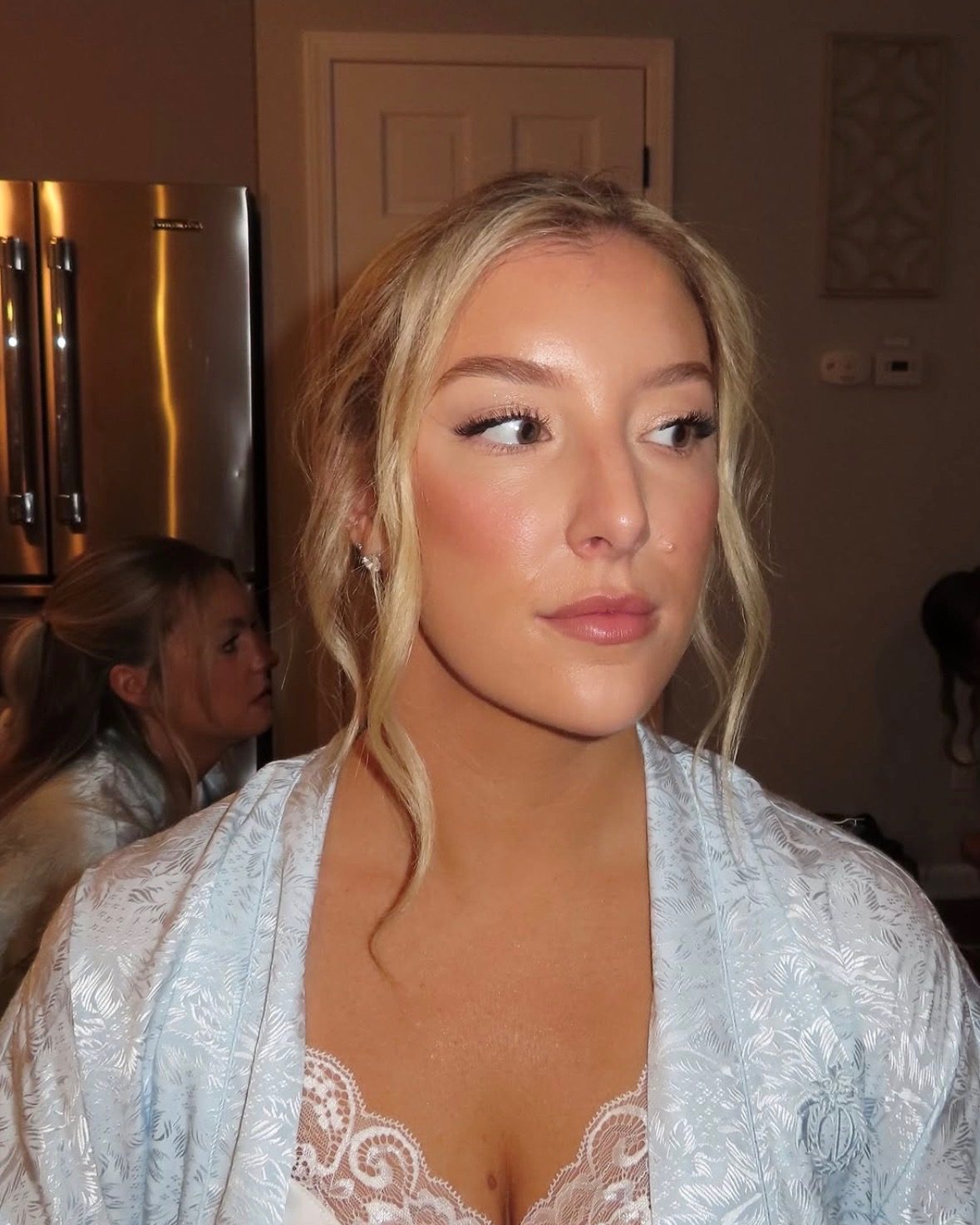 Client with luminous dewy glam makeup, soft glow and warm tones, getting ready