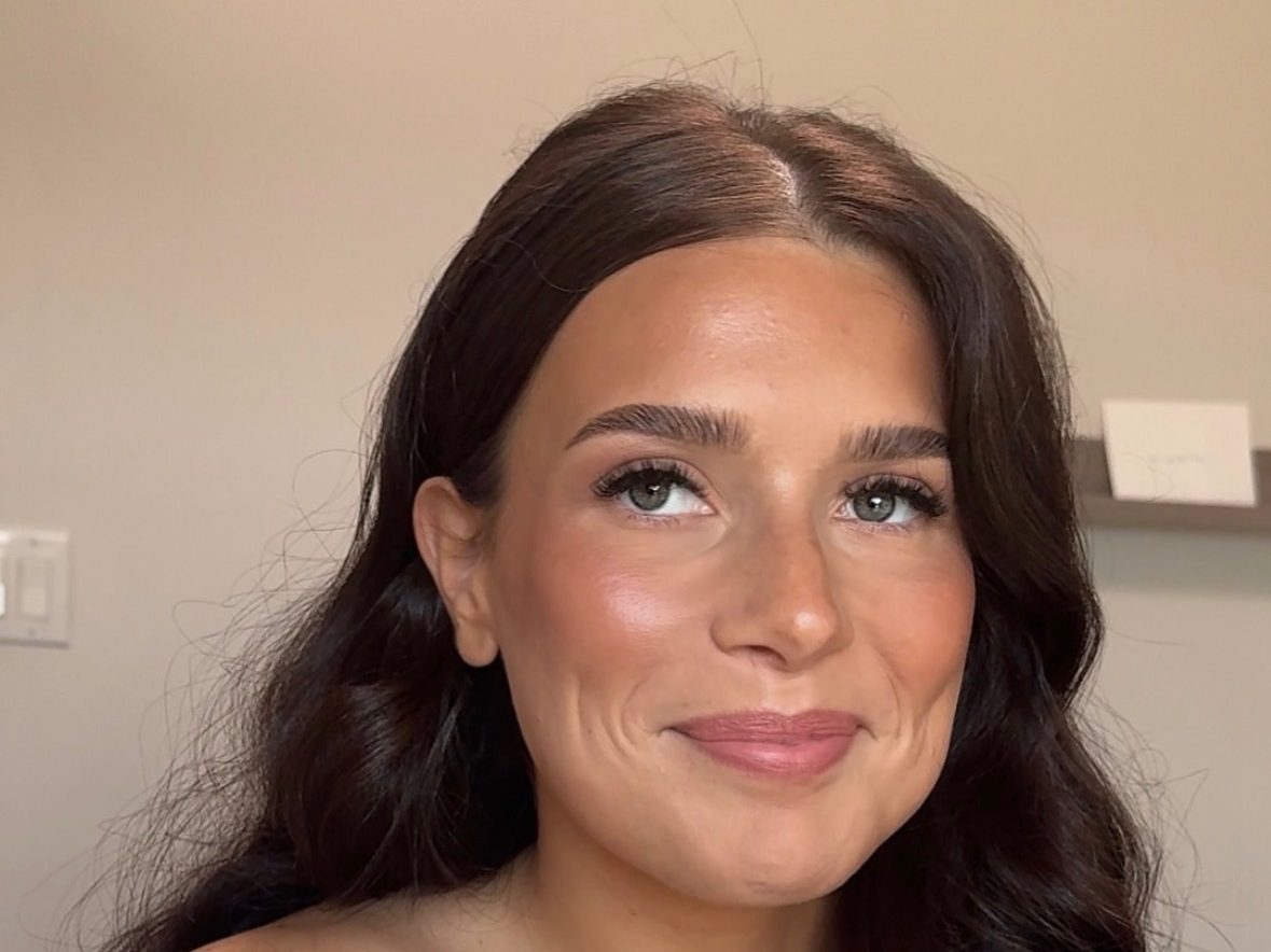 Samantha applying a precise lip during a session — a client looking up as the color goes on