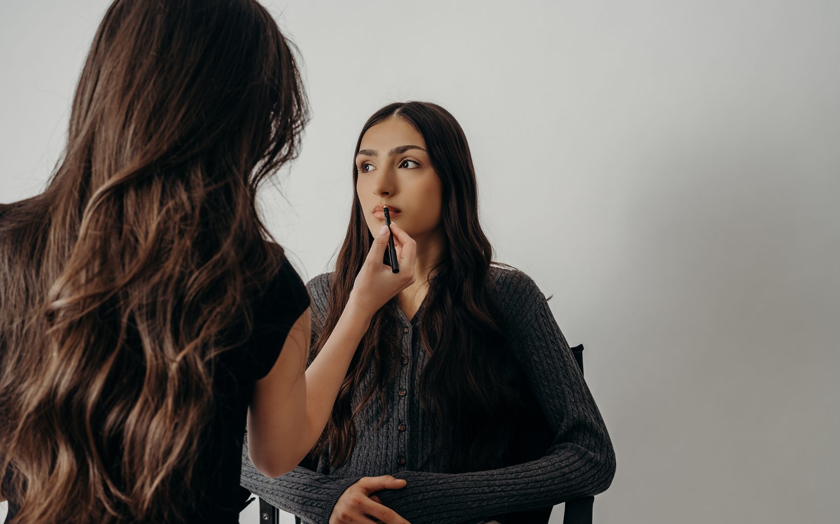 Samantha applying a precise lip during a session — a client looking up as the color goes on